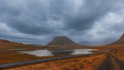 Scenic view of Kirkjufell Mountain in West Iceland with dark stormy clouds.