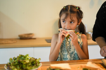 Child eating fresh bread with lettuce, representing healthy breakfast habits at home