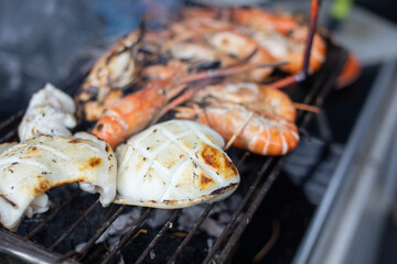 Squid and shrimp are grilled on a metal grill, close-up photo.