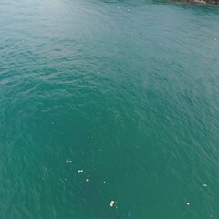 Obraz premium Overhead view of teal ocean water with scattered debris