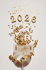 2026 New Year firework or toast with golden numbers from champagne glass with festive party decoration top view.