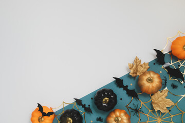 Halloween holiday background with party decorations of pumpkins, golden spiderweb and bats top view. Happy halloween greeting card in flat lay style.