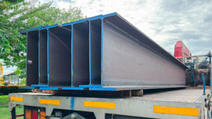 Wide flange steel beams arranged in a construction yard, essential for heavy-duty structural...