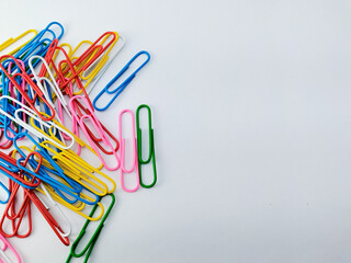 A collection of colorful paperclips scattered on a light surface. 