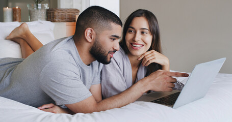 Laptop, happy and couple on bed in home with watching movie, film or series together on weekend. Smile, technology and man with woman streaming show on website for bonding in bedroom at apartment.