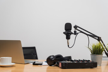 Podcast studio desk with microphone, laptop, headphones, audio mixer, smartphone and coffee cup...