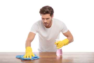 Young man cleaning a wooden table with spray and cloth.