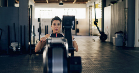 Athlete, woman and fitness with rowing machine at gym of exercise, strength training and workout....