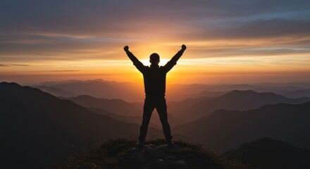 Silhouette of man celebrating victory with arms raised at sunset mountain range peak