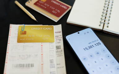 close up shot, credit card with receipt ,financial bills and mobile screen is showing calculator...