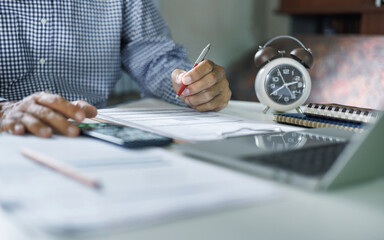 asian businessman working on desk checking business document using mobile with laptop working online