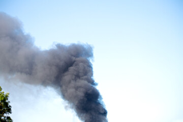 Black smoke rising into the empty blue sky. Fire or forest fire. Emergency idea concept. Environmental disaster or global warming. Nature destruction. Copy space.