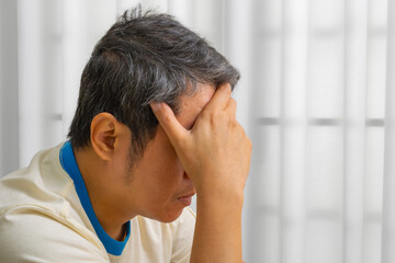 Stressed Asian middle-aged man with headache from work pressure; medical concept of tension-type...