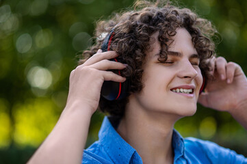 Waist up of a curly-haired teen wearing headphones