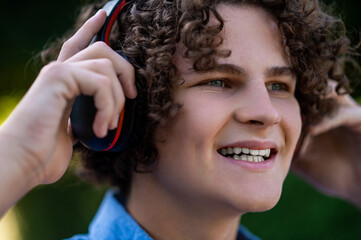 Waist up of a curly-haired teen wearing headphones