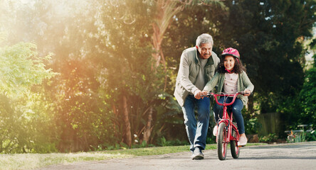 Teaching, grandfather and child on bicycle outdoor with safety, learning skills and development....