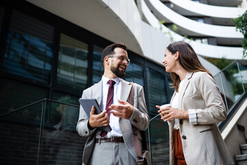 Business people talking and smiling outside office building