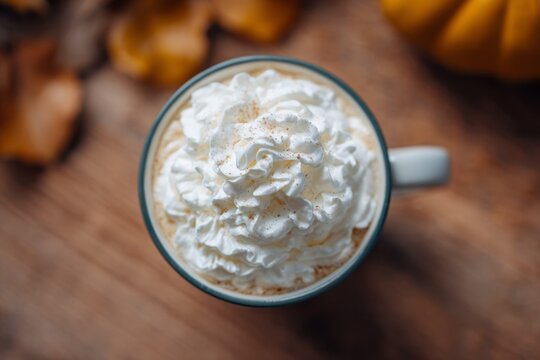 Creamy swirls crown a pumpkin spice latte, autumn ritual indulgence for warm cozy Hygge moments and Samhain celebrations