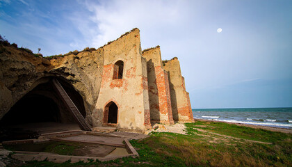 Fototapeta premium Weathered Brick Buttresses of a Coastal Ruin Under a Pale Moon