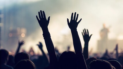 Hands silhouettes raised high in the air — cheering crowd at live music concert