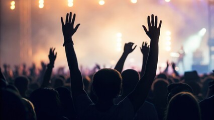 Fototapeta premium Silhouetted crowd with hands up — music lovers immersed in vibrant show