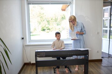 Music piano teacher and a boy learn how to play the piano