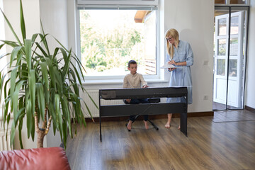 Music piano teacher and a boy learn how to play the piano