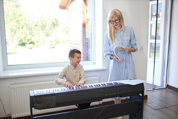 Music piano teacher and a boy learn how to play the piano