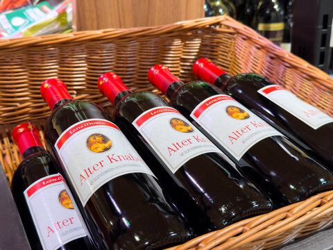 Villach, Austria - August 18, 2025: Bottles of Alter Knaus wine displayed in a wicker basket, showcasing the rich color and elegant label design in a retail environment