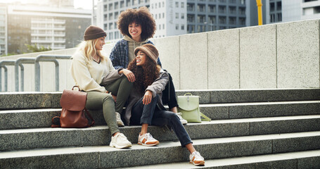 Conversation, city and girl friends on stairs with fashion for trendy, cool and modern clothes on holiday. Happy, steps and female people with stylish outfit in urban town on vacation or weekend trip