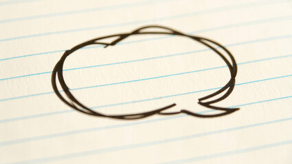 Scribbled messy doodle speech bubble on notebook background.