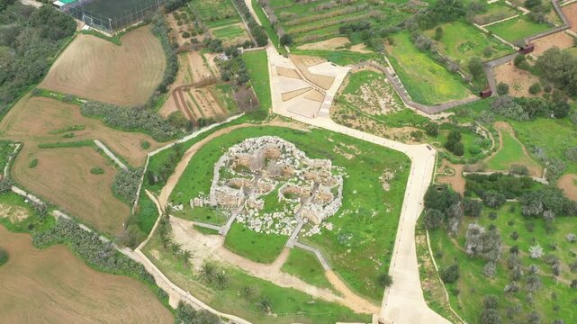 Drone shot of Ggantija Archaeological Park in Gozo with ancient stone temple ruins on green land