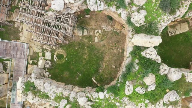 Drone shot of Ggantija Archaeological Park in Gozo with ancient stone temple ruins on green land