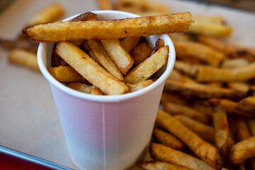 potato chips or french fries in a paper cup and on a tray in a fast food restaurant