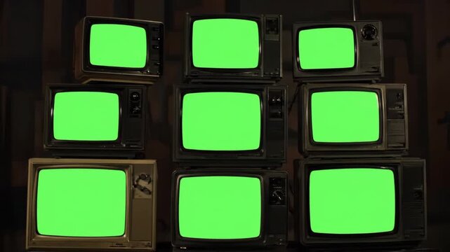 Stack of Vintage TVs with Green Screens - 9 old televisions with green screens are stacked against a dark background.