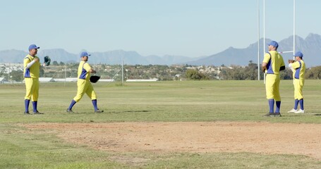 Raising glove, diverse male teammates practicing catch-and-throw drill in outfield, with baseballs
