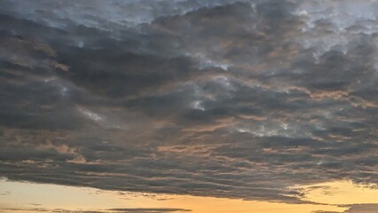 A textured sky with dramatic, layered clouds. The top half is a moody blend of dark gray and blue,...