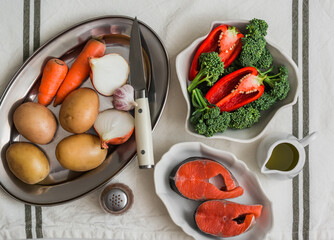 Ingredients for making a thick rich fish soup with potatoes and broccoli on a light background, top...