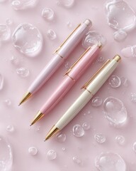 Elegant pastel pens arranged on a soft pink background with water droplets for writing enthusiasts and stationery lovers