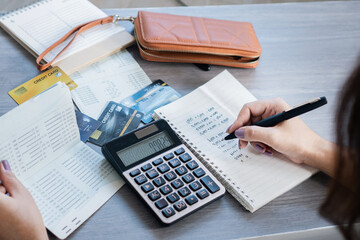 woman hand doing accounting writing debt list in notebook, using calculator manage expenses,...