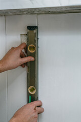 Male hands using spirit level to check board surface. Construction worker adjusting level tool on...