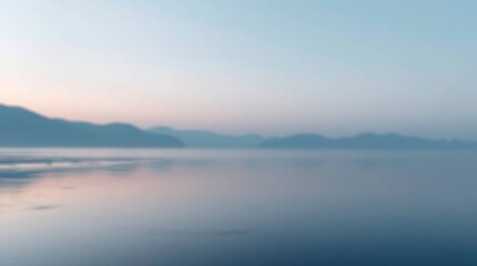 Fototapeta premium A blurry landscape with mountains and a lake possibly at dusk or dawn