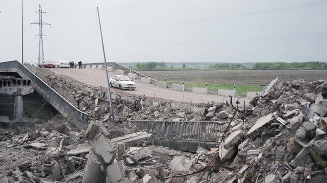 Bucha, Ukraine - 05 15 2022: Damaged road bridge as result of russian army invasion in Kyiv region. Civil cars passing dangerous plots during evacuation from abandoned ities.