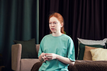 Young woman sitting thoughtfully in a cozy living room during afternoon