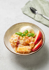 Peach crumble or cobbler with vanilla ice cream scoops and cinnamon on a plate on a light background