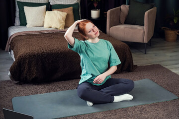 Woman engaging in stretching exercises in a cozy bedroom setting during morning hours