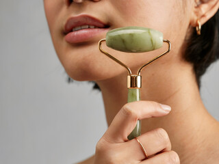 Woman using jade stone jade roller for facial massage beauty skincare wellness and rejuvenating natural selfcare treatment