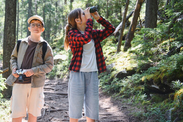 Young tourists exploring nature with binoculars and camera
