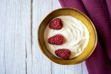 Porcelain bowl and natural yogurt with red berries on the wood table.
