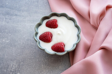 Green porcelain bowl and natural yogurt with berries on the stone marble table.